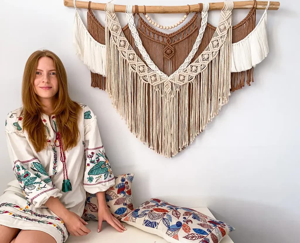 Anna sitting beside a cream and brown macramé wall hanging